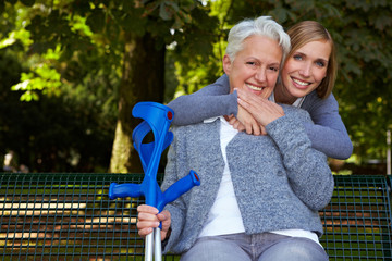 Frau umarmt Seniorin mit Krücken