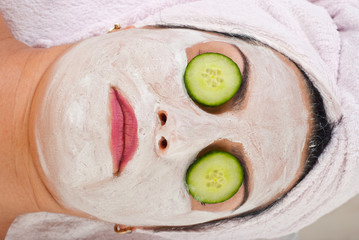 Detail of woman with facial mask and cucumber