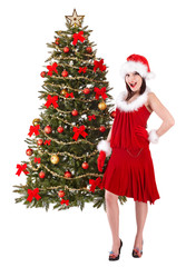 Girl in santa hat by christmas tree. Isolated.