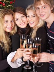 Group young people drinking champagne by christmas tree.