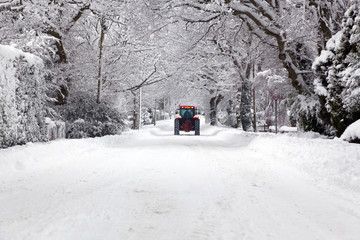 Tractor driving down a snow covered road