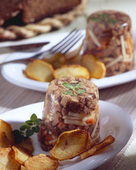 Goose aspic on a white plate with potatos.