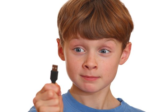 Irritierter Junge schaut auf einen USB-Stecker