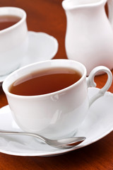 Black tea in mugs with saucers