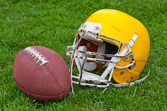 Football helmet and ball on a grass
