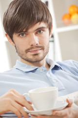 man with cup tea on sofa