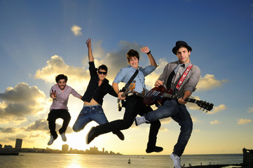 Group of young male musicians jumping with instruments