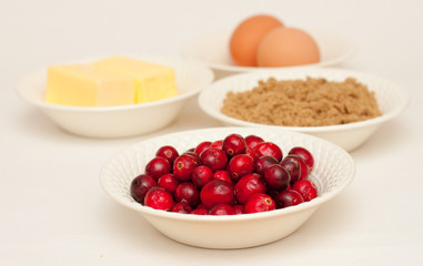 Four bowls of ingredients : eggs, butter, sugar, cranberries