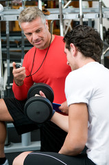 Fototapeta na wymiar Young man with instructor at gym