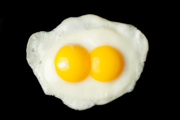Fried two-yolks egg on black background