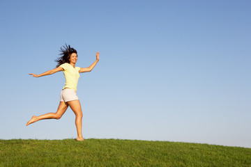 Young woman running through field