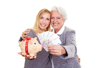 Oma und Enkelin halten Geld und Sparschwein