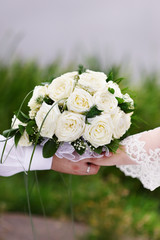 Bouquet of white roses in hand of groom and bride