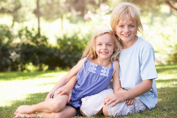 Brother and sister pose in a park