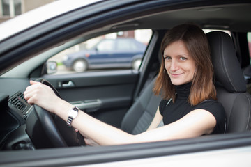 Pretty young woman driving her new car (shallow DOF; color toned