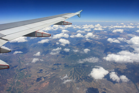 Airplane wing, aerial view with mountains and clouds