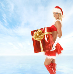 Obraz premium A young blond in a Santa costume holding a present