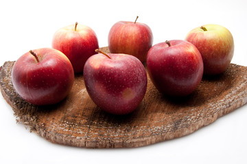 Äpfel auf rohem Holzbrett vor weissem Hintergrund