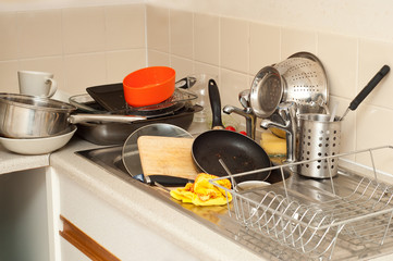pile of dirty dishes in the metal sink