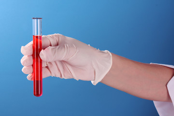 Test tube in hand over blue background