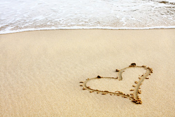 hearts drawn in the sand with seafoam and wave