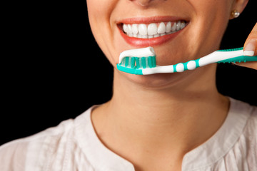 Woman healthy teeth closeup with toothbrush on black background