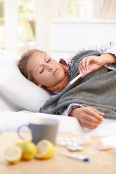 Young female having flu laying in bed