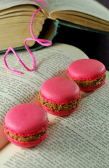 Filled french pink macarons on an antique recipe book