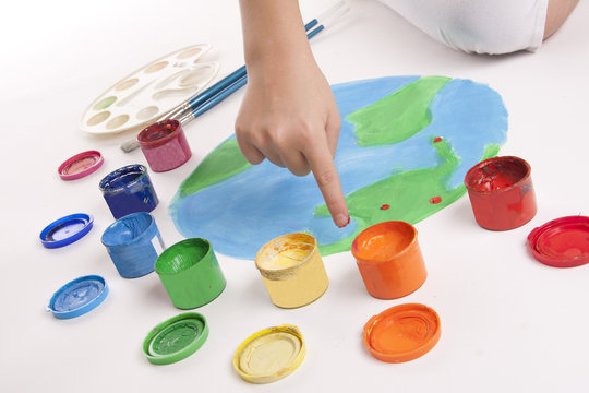 child draws colored paints globe