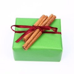 Gift in green wrapping with a red bow with cinnamon sticks