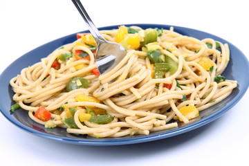 Spaghetti with vegetables being eaten with a fork on white