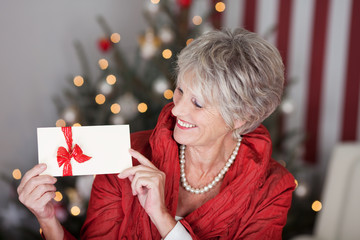 rentnerin mit gutschein vor dem weihnachtsbaum