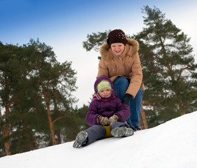 Fototapeta na wymiar child sliding in the snow with her mother