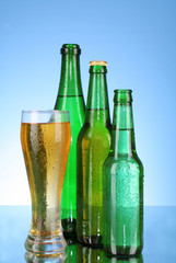 Bottles with beer and cup on blue background