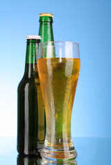 Bottles with beer and cup on blue background