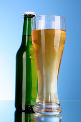 Bottle with beer and cup on blue background