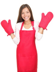 Cute smiling young housewife with cooking mittens isolated