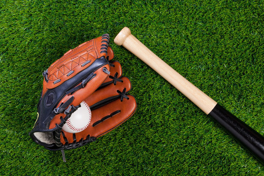 Baseball glove bat and ball on grass