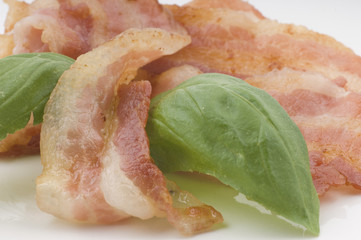 fried bacon stripes closeup decorated with green herbs