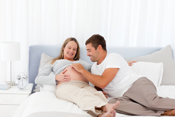 Fototapeta premium Cute man playing with his pregnant wife