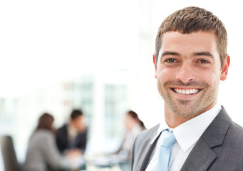 Businessman smiling at the camera while his team is working