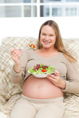 Obraz na płótnie Canvas Cheerful pregnant woman eating vegetables