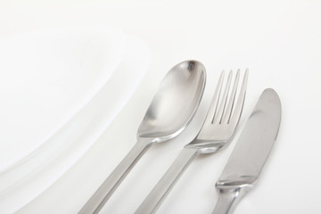 fork, spoon and knife with white plates on background