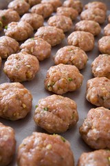 tray of raw meatballs on a baking sheet