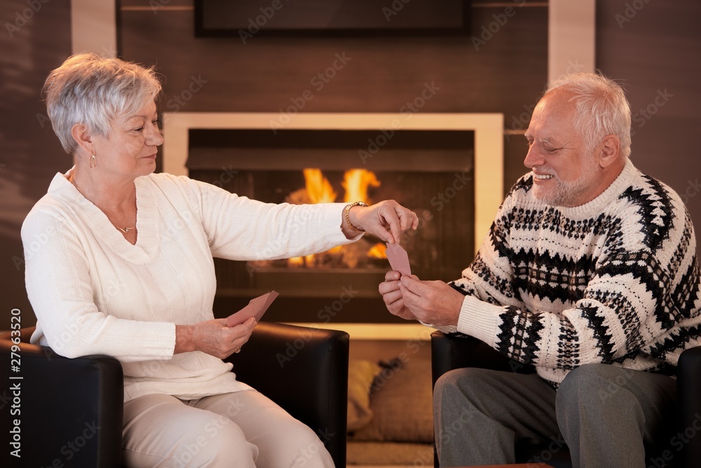 Wall mural Senior couple playing cards on winter night