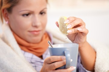 Young woman having flu drinking tea feeling bad