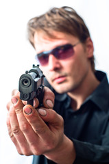 Man holding gun in dirty hands with focus on pistol  weraing sun