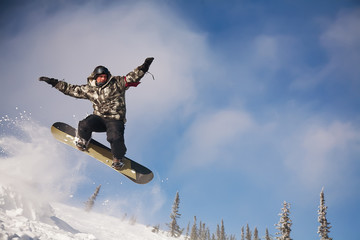 Snowboarder jumping through air with  blue sky in background