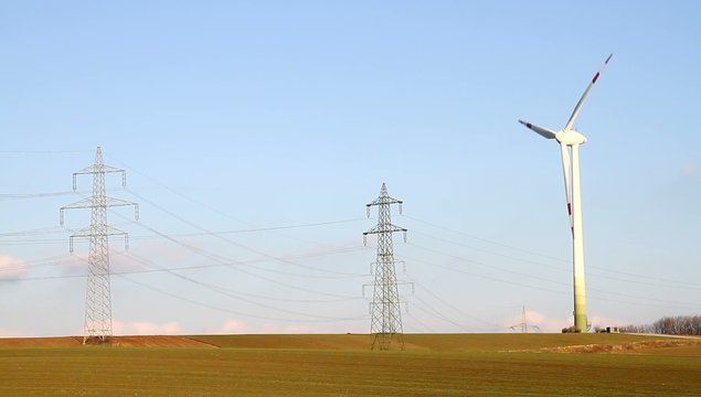 Windkraftwerk neben Strommasten
