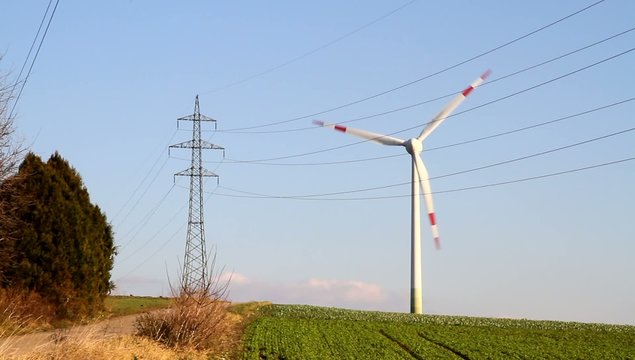 Windkraftwerk neben Strommast
